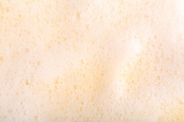 White fluffy foam on yellow background, top view