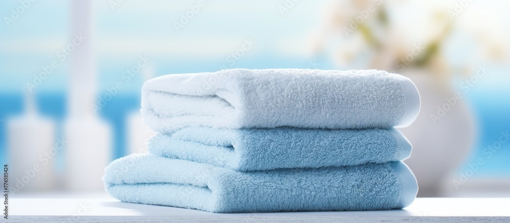 Poster neatly folded towels arranged in a pile on a wooden table, ready for use and display in a bathroom o