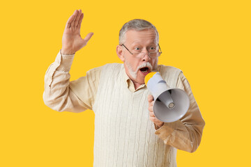 Shocked senior man with megaphone on yellow background
