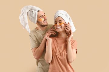 Young loving couple after shower with under-eye patches on beige background