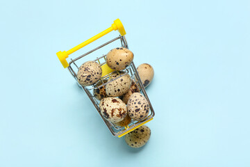 Shopping cart with fresh quail eggs on blue background