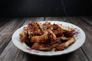 Pile of grilled chicken thigh serving on the plate. Famous roast cutting meat menu in Asia restaurant. 