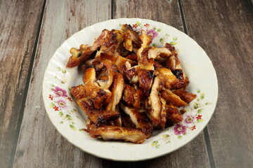Pile of grilled chicken thigh serving on the plate. Famous roast cutting meat menu in Asia restaurant. 