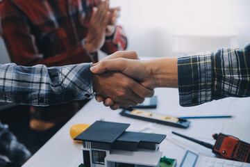 Architect and engineer construction workers shaking hands while working for teamwork and...