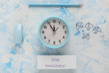 Paper with text TIME MANAGEMENT, alarm clock and stapler on blue grunge background. Top view