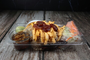 Meal or lunch box. Traditional fried shrimp paste with rice and topping with omelete, roasted sausage and sweet pork. Famous street food menu in plastic container.
