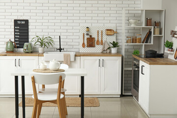 Stylish light kitchen with pegboard and modern dining table