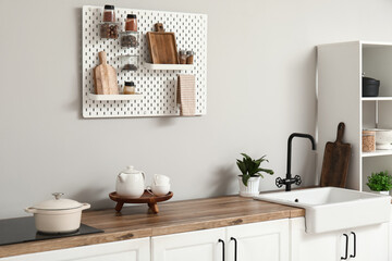 Stylish light kitchen with pegboard and kitchenware - obrazy, fototapety, plakaty