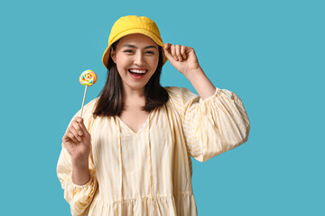 Happy young woman with sweet lollipop on blue background