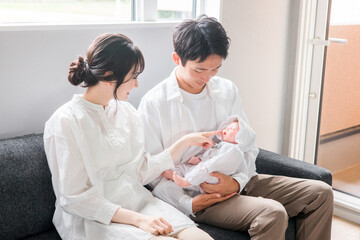 赤ちゃんを抱く夫婦・ママとパパ・新生児（子育て・育児）
