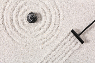 Fototapeta na wymiar Rake and stone on sand with lines in Japanese rock garden, top view. Zen concept