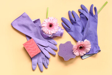 Latex gloves with sponges, garbage bags and spring flowers on beige background