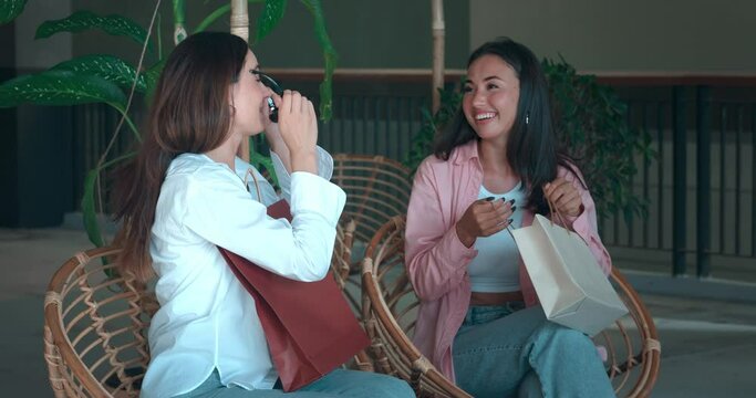 Two friends on bench showcasing new purchases sharing joy of shopping. Joy of shopping reflected in laughter smiles Joy of shopping women's friendship Celebrating shared tastes joy in new finds.