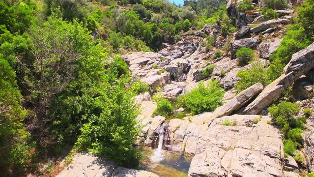 Waterfall spring from cliff mountains rocks on Ikaria island, Greece in summer with nature landscape view at longevity blue zone