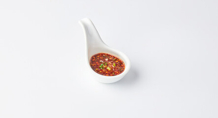 Thai chili sauce (Nam jim jaew) served on white spoon cup isolated on white background. It’s made with fish sauce, sugar, and lime, good for grilled meats. spicy, sweet, salty and sour taste.