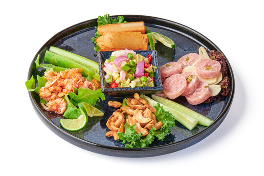 Sliced pork sausage, cashew nuts, dried shrimp, fried pork sausage and a dipping sauce consisting of chilli, lime and shallot isolated on white background. Thai people eat this appetizer with alcohol.