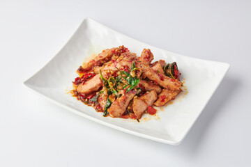 Thai spicy stir-fried grilled pork neck (Pork Jowl) with holy basil leaves served in white plate isolated on white background. Hot and spicy.