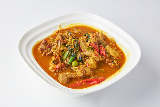 Chicken jungle curry served in white bowl isolated on white background. Hot and spicy chicken soup with herbs and vegetable Thai style.