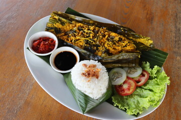 asian traditional food talapia fish  steam with spicy and turmeric wraping with  banana leaf  and steam rice 