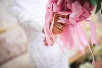 Bride's hands with ring and flowers.