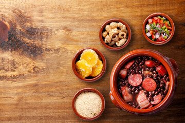 Fototapeta na wymiar Brazilian feijoada, traditional food from Brazil cuisine, on ceramic casserole bowl, over rustic wooden table