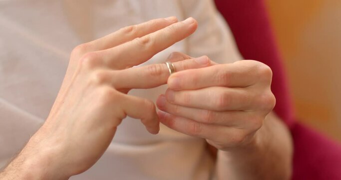 Close-up of hand removing wedding ring, symbolizing union dissolution. Emotional separation concept. Male hand removes wedding ring, signifying end of union. feelings of loss, transition, and closure.