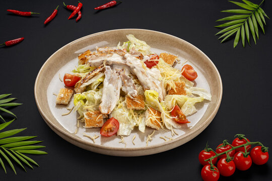 Salad with chicken fillet, tomatoes, lettuce, cheese, crackers and sauce on a round plate. View from above. Food photos for cafes.