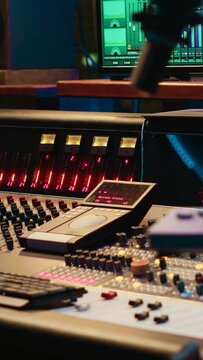 Vertical Video Control room with technical equipment and music recording software, professional studio editing and producing tracks. Audio console with moving faders and colored meters, high quality