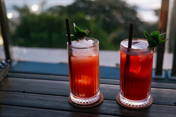 two cocktails with ice and mint on the wooden table 