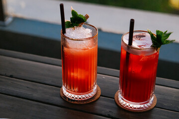two cocktails with ice and mint on the wooden table 