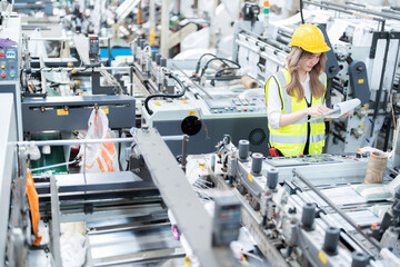 Asian female engineer looks at list of export orders standing near the circuit board of a...