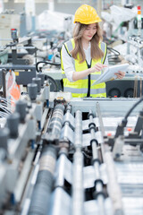 Vertical shot of female engineer supervising work in Asia as a supervisor in an industrial company producing automobiles and robots, checklists with modern machines in a European factory. - obrazy, fototapety, plakaty