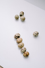 Quail eggs that are the size of an adult human's thumb are lined up on a white mat for photographic and detailed purposes.