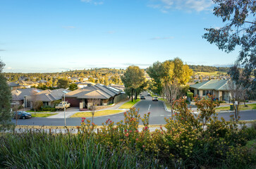 a residential neighborhood with single-story Australian houses lining a quiet street, a lived-in...
