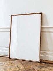An empty picture frame leaning against a white wall on a wooden floor, adding a touch of minimalistic elegance to any interior space. 