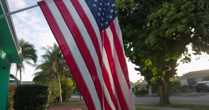 USA Flag hanging with pride in front of average american home at sunrise
