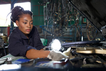 mechanic using flashlight for checking and fixing a car in automobile repair shop