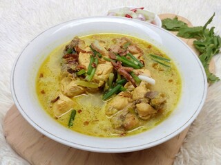 Gulai ayam or chicken curry served in a white bowl. A soupy dish made from chicken cooked with spices and coconut milk. Indonesian traditional cuisine.