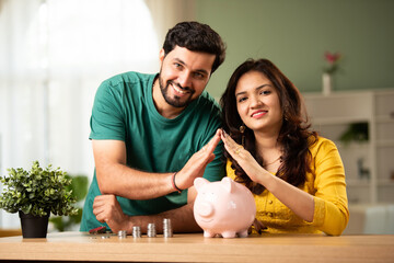 Indian couple saves money in piggy bank for home buying, saving concept