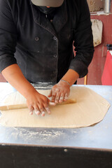Obraz na płótnie Canvas Hands of pizza maker man kneads dough, prepares and shapes for pizza base with rolling pin and flour