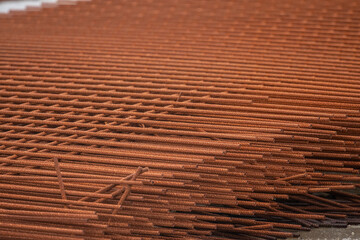Pile of rusty rebar on concrete floor.