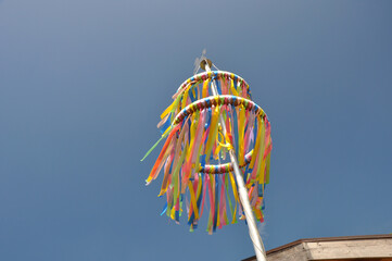 Bunte Pfingstkränze aus Tradition zum christlichen Fest: Die farbenfrohen Bändern wehen sanft im Frühlingswind vor blauen Himmel.