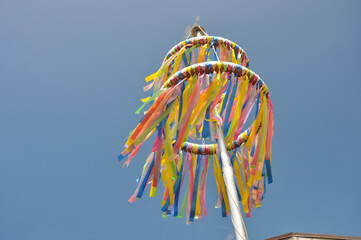 Bunte Pfingstkränze aus Tradition zum christlichen Fest: Die farbenfrohen Bändern wehen sanft im Frühlingswind vor blauen Himmel.