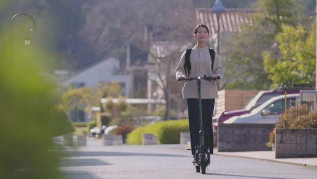 住宅街を電動キックボードで移動する日本人の女性