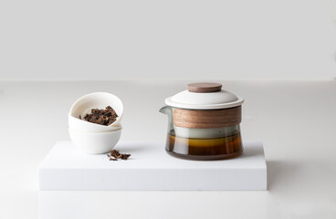 Minimalist still life tea concept, Oriental style teapot and cups with dry tealeaves on white podium - 776895216