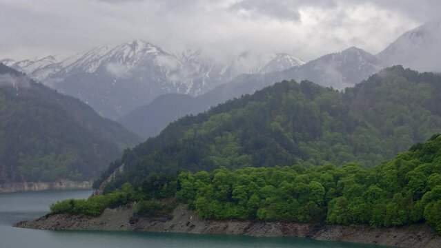 Heavy rain and clouds over a lake with distant snow covered mountains