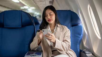 An attractive Asian businesswoman turn on the airplane mode on her smartphone before takeoff.