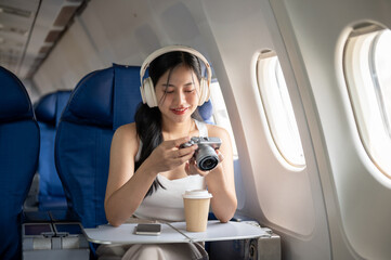 Fototapeta premium A female passenger is checking pictures on her camera during the flight of her summer vacation.