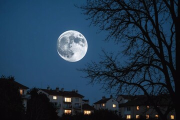 Naklejka premium Moon rising over trees and buildings at night