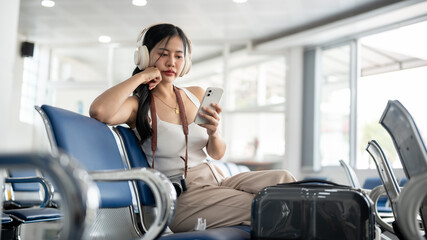 A female passenger is feeling bored while waiting for her boarding call in the airport terminal.